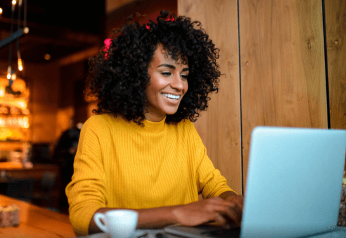 Mulher sorrindo e trabalhando em um notebook.